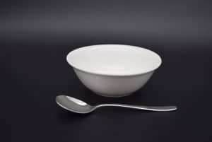 A white 6" small bowl with a dessert spoon