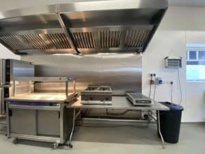A small kitchen set up using hire items including a stainless steel table and light gantry, a black bin and a hot cupboard. All these items can be hired from YES Hire