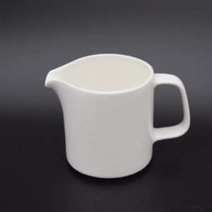 A white milk jug on a black background