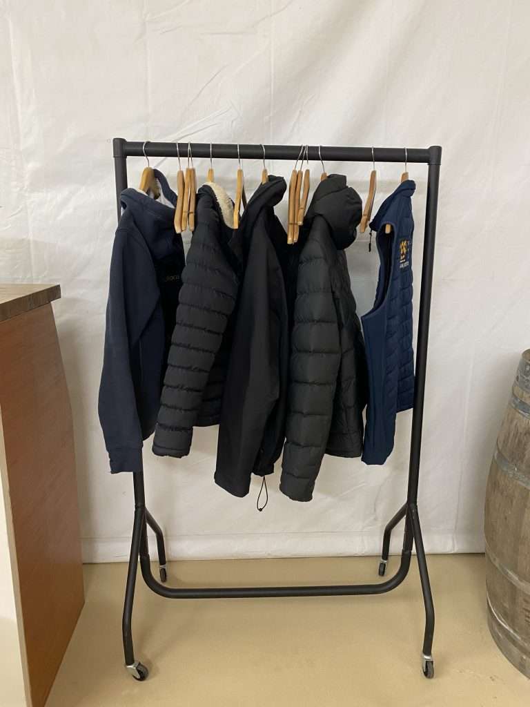 A black coat rail on hire in Ripon. There are several coats and jackets on the rail