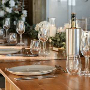 Table glasses set on a rustic wooden table with fine dining plates all available from YES Hire