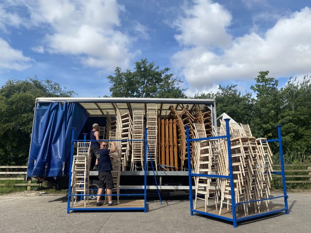 A wagon is loaded outside YES Hire. Inside the wagon are lots of limewash chairs available for hire
