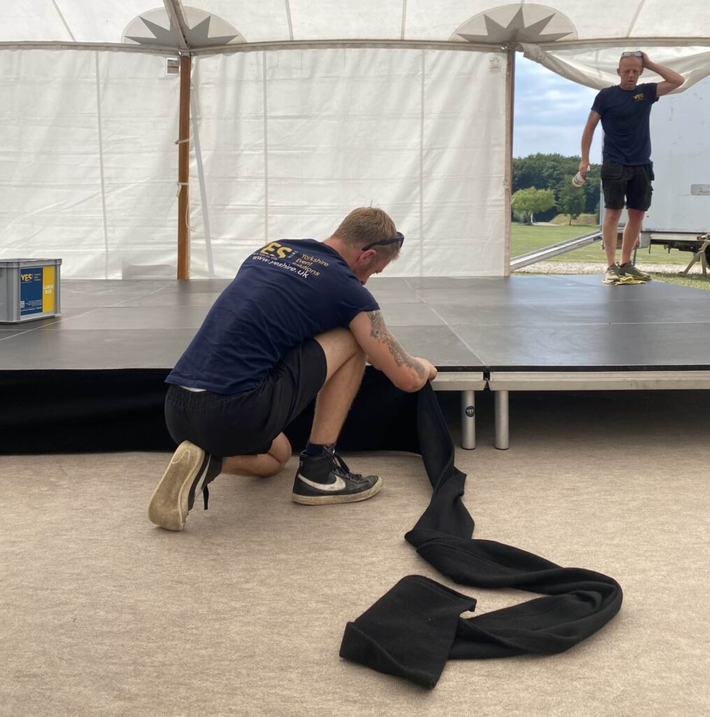 A YES Hire staff member attaches valance to a stage