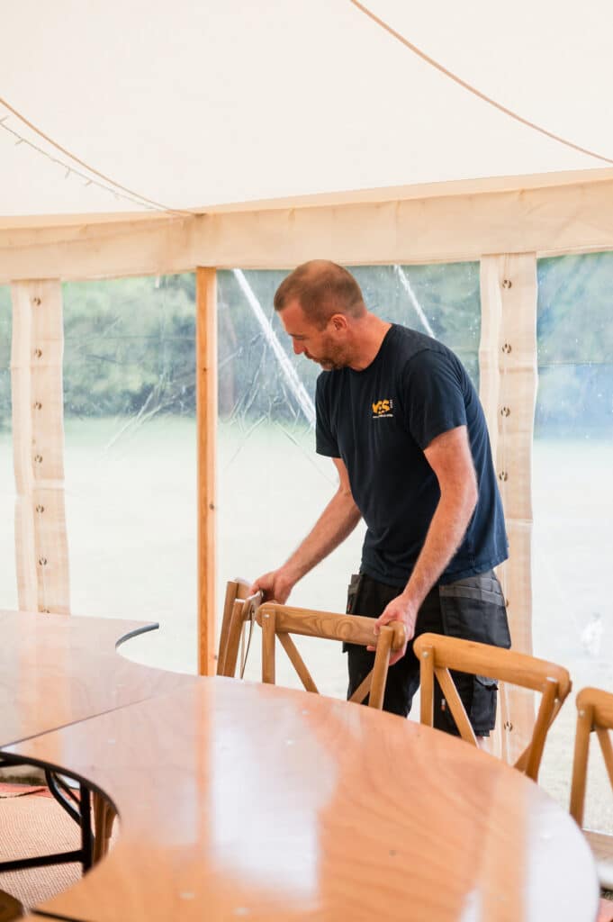 YES Hire Staff member adjusting chairs in a wedding marquee